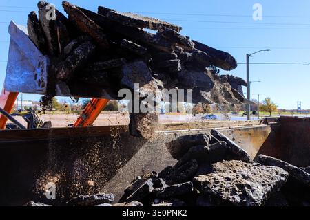 Die Arbeiter entfernen alten Beton von der Baustelle, um Platz für neuen Bürgersteig zu schaffen, wenn Fahrzeuge vorbeifahren. Stockfoto