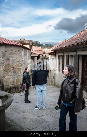 Junge Reisende erkunden die historischen Kopfsteinpflasterstraßen von Combarros, vorbei an traditionellen Steinhäusern mit Terrakottadächern in einem bezaubernden galizischen Dorf Stockfoto