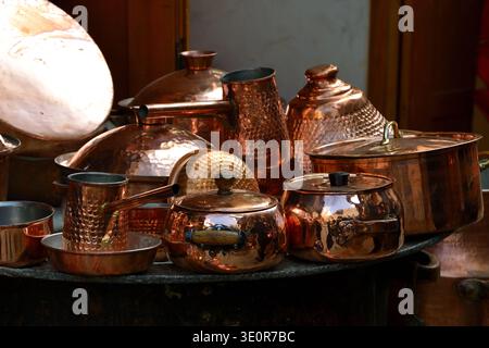 Glänzende Kupferkochtöpfe und -Utensilien, die auf dem Markt ausgestellt werden, mit reichhaltiger metallischer Textur und Wiederholung Stockfoto