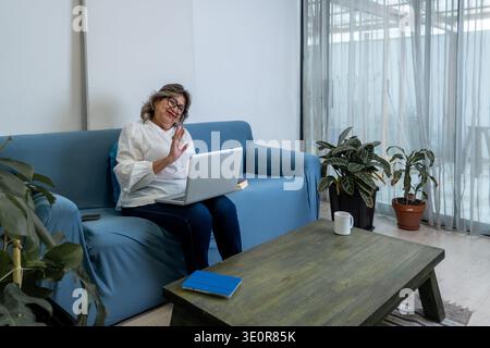 Eine Seniorin zu Hause, die einen Videoanruf auf einem Laptop führt und sich mit der Familie verbindet Stockfoto
