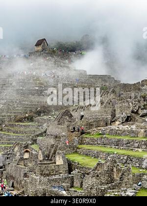 Wolken Rollen über die antike Stadt Macchu Pichu, während die Hütte der Wächter kurz erscheint. Stockfoto