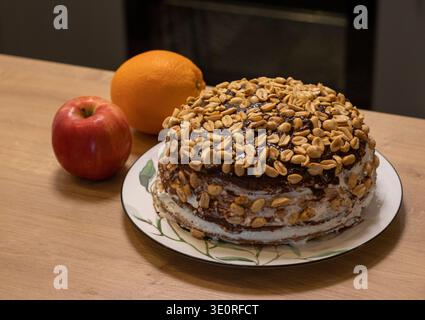 Ein mehrschichtiger Kuchen, der mit Schokoladenglasur bedeckt ist und mit einer großen Menge gerösteter Erdnüsse belegt ist Stockfoto