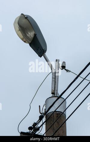 Ein Versorgungsmast mit einer Leuchte oben. Der Pol steht vor einem bewölkten Himmel. Stockfoto