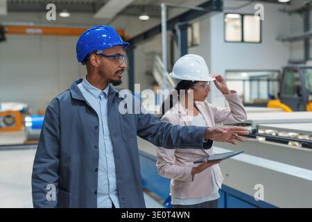 Zwei Fachleute überprüfen den Produktionsprozess und prüfen die Maschinen in einem modernen Fabrikumfeld. Stockfoto