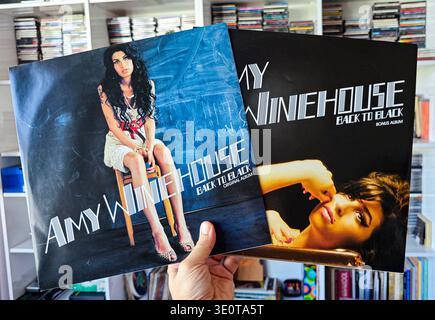 Hand hält zwei Amy Winehouse Back to Black Vinyl-Alben und zeigt das Original- und Bonusalbum-Cover in einer eigenen Bibliothek. Stockfoto