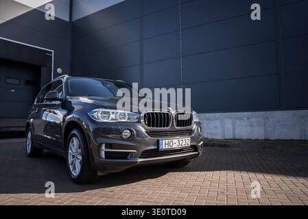 BMW X5 Dreiviertelansicht durch Industriegebäude bei Tageslicht in Lettland Stockfoto