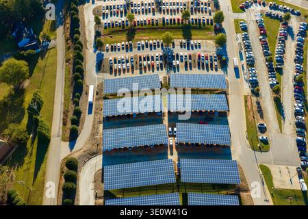 In die städtische Infrastruktur integrierte Solarstromerzeugung. Photovoltaikpaneele als Schattendach über dem Parkplatz mit geparkten Autos installiert Stockfoto