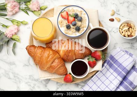 Gesundes Frühstück. Flache Komposition mit leckeren Croissants und Haferbrei mit Beeren auf weißem Marmortisch Stockfoto