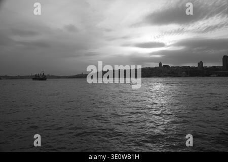 Schwarz-weiß-Blick auf Istanbuls Skyline bei Sonnenuntergang über dem Wasser. Stockfoto