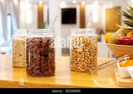 Gläser mit verschiedenen Frühstückszerealien, Müsli, Schokoladenschalen und Puffkörnern auf dem Hotelbüfett Stockfoto