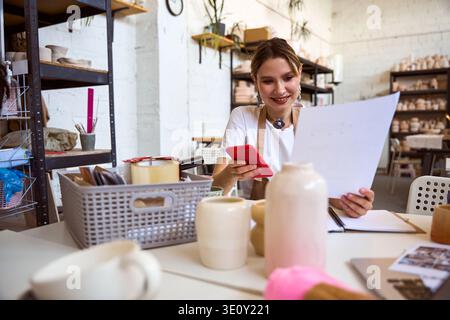 Junge ostasiatische Frau im Töpferstudio, lächelnd und konzentriert Stockfoto