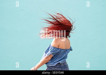 Attraktive junge Frau in Sommerkleidung und Sonnenbrille, tanzt auf blauem Hintergrund auf der Straße || Model veröffentlicht Stockfoto