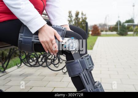 Frau mit Sportkleidung und Kniebeuge oder Orthese nach Beinoperationen, Spaziergang im Park. Medizin- und Gesundheitskonzept. || Modell freigegeben Stockfoto