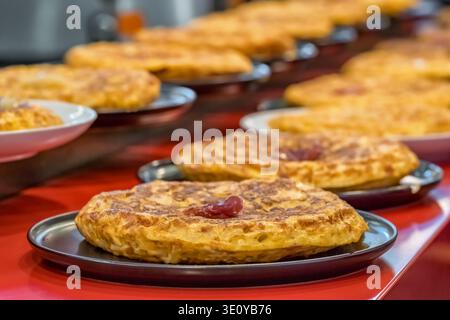 Reihe traditioneller spanischer Kartoffeltortillas mit Marmelade auf Tellern Stockfoto