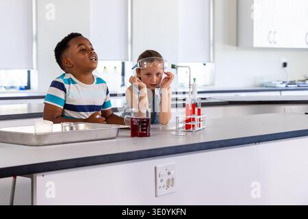 Diverse Kinder, die Experimente im Schullabor durchführen, mit Becher, Reagenzglasgestell, Schutzbrille Stockfoto