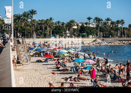 Cannes, Frankreich - 15. September 2025: Menschen, die sich an einem belebten öffentlichen Strand am Mittelmeer in Cannes an der französischen Riviera entspannen und schwimmen Stockfoto