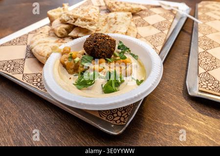 Traditionelle ägyptische Falafel mit Hummus, Kichererbsen, Tahini, Kräutern und warmem Pitabrot auf einem rustikalen Tisch. Authentisches mittelöstliches Street Food, gesunde pflanzliche Küche. Stockfoto