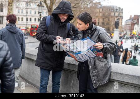 London, Großbritannien, 2. Dezember 2025, reife Touristen, die auf einer Stadtstraße in London auf eine Karte und ein Smartphone blicken. Stockfoto