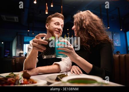 Glückliches Paar mittleren Alters, das am Abend im Restaurant Cocktails toast Stockfoto