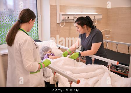 Zwei Frauen im Gesundheitswesen, die Kinder im Krankenhaus betreuen Stockfoto