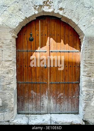 Eingangstür des traditionellen nahöstlichen Steinhauses. Eiserne schmiedeeiserne Holztür in einer Straße der Stadt im Nahen Osten. Straßen von Mardin, Türkei Stockfoto