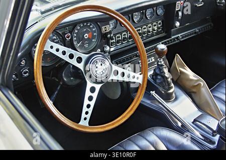 Innenansicht eines klassischen Jaguar E-Type mit Schwerpunkt auf Lenkrad aus Holz, Armaturenbrett und Schaltstange Stockfoto
