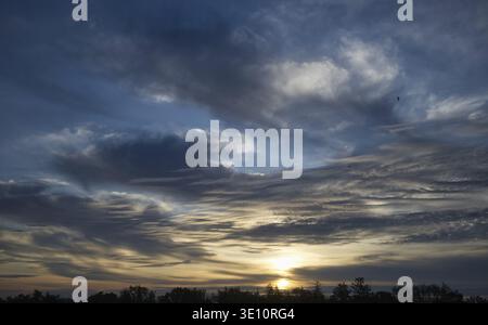 Herrliche Sonnenuntergangsszene mit dramatischen Wolken, lebhaften Farben, Silhouetten von Bäumen und einer ruhigen Atmosphäre, die Natur und Schönheit miteinander verbindet Stockfoto