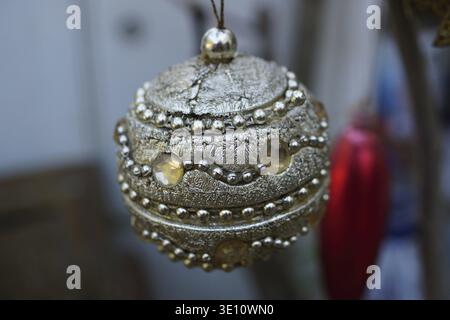 Silberne weihnachtskugel mit gelben Dekorationen, die mit einem verschwommenen Hintergrund hängen Stockfoto