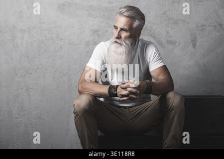 Stilvoller und hübscher bärtiger älterer Mann, der im Studio posiert Stockfoto