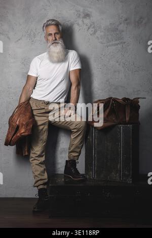 Stilvoller und hübscher bärtiger älterer Mann, der im Studio posiert Stockfoto