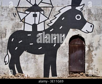 Schwarze Esel-Zeichentrickzeichnung auf einer weißen Wand mit einer Windmühle als Hut Stockfoto