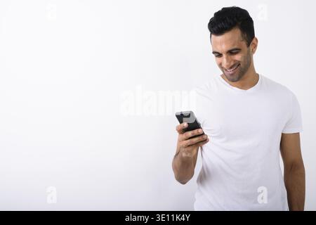 Studio shot der jungen schönen Indischen mit Handy vor weißem Hintergrund Mann Stockfoto