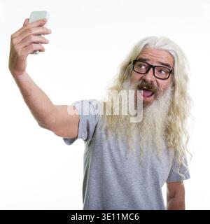 Studio shot von Happy älterer bärtiger Mann lächelnd während der Einnahme von selfie Bild mit Handy Stockfoto