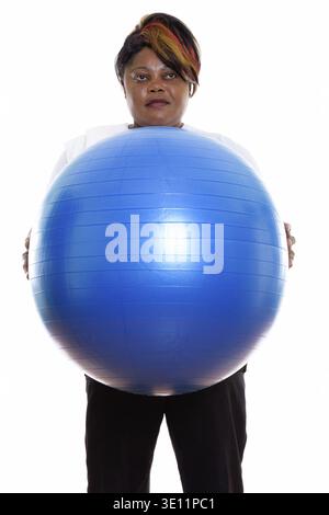 Studio-Aufnahme von fetten schwarzen afrikanischen Frau denken und stehen Während Sie den Gymnastikball für das Fitnessstudio bereit halten Stockfoto