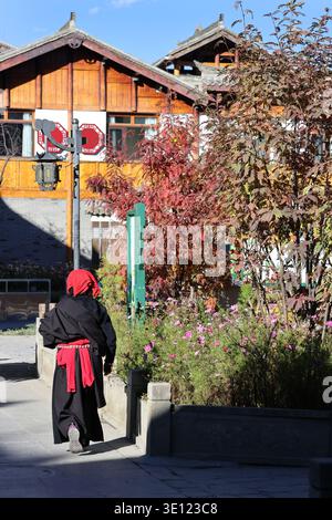 Rückansicht einer tibetischen Frau in traditioneller Tracht, die in der antiken Stadt Songzhou im Kreis Songpan in der chinesischen Provinz Sichuan spaziert Stockfoto