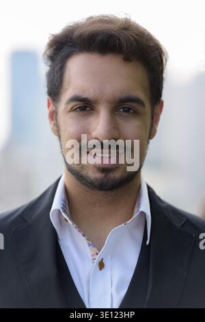 Gesicht der jungen indischen Geschäftsmann zufrieden lächelnd im Freien in der Stadt Stockfoto