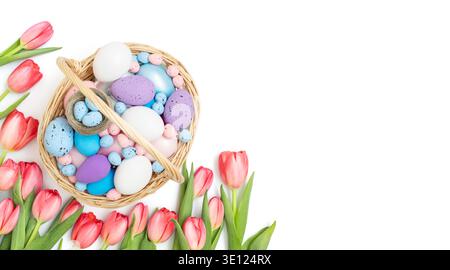 Osterkorb mit bemalten Eiern und rosa Tulpen auf weißem Hintergrund. Wunderschöne Osterkomposition. Banner. Kopierbereich, Draufsicht, flache Ladefläche. Stockfoto