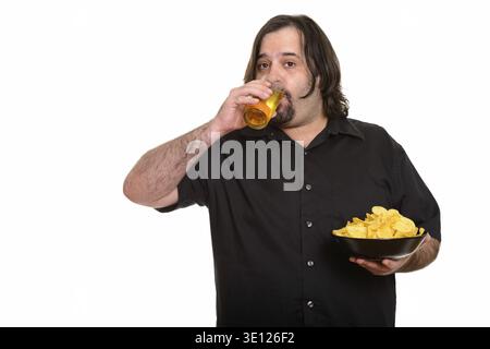 Fetter Kaukasier trinkt Bier, während er eine Schüssel Chips vor weißem Hintergrund hält Stockfoto