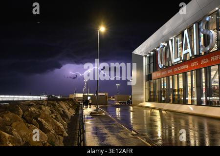 Ein kräftiger Blitz beleuchtet den Himmel über dem Hafen von Calais und dem Haupteinkaufskomplex der Fähre während eines schweren Gewitters im Frühling. Stockfoto