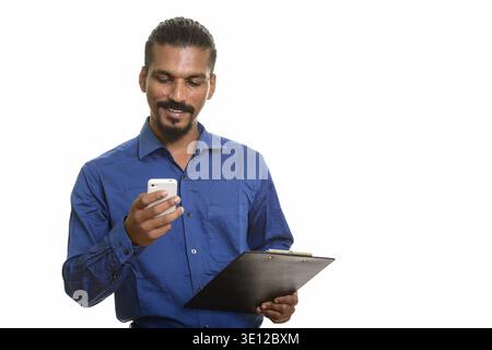 Junge glücklich indischer Geschäftsmann mit Mobiltelefon, während Sie die Zwischenablage Stockfoto