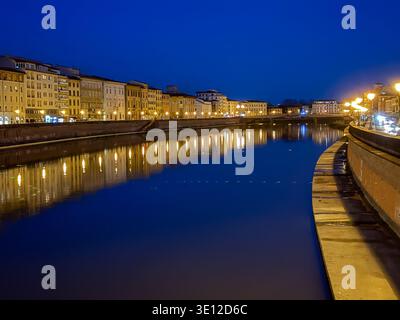Fluss Arno in Pisa, Italien, während der tiefblauen Stunde mit beleuchteten historischen Gebäuden, die sich auf dem Wasser spiegeln. Stockfoto