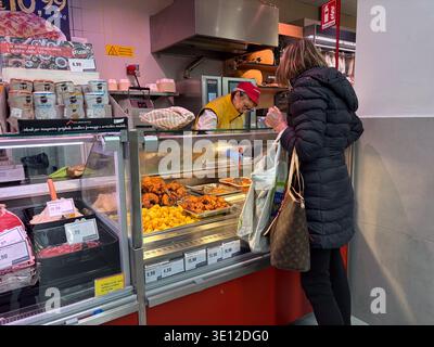 Eurospin-Supermarkt. Pisa, Italien. Kunde kauft zubereitete Speisen vom Server an der Frischfleisch- und Feinkosttheke. Alltägliche Einkaufsszene. Stockfoto