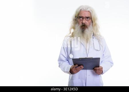 Studio shot der älteren bärtigen Mann Arzt denken, während Sie die Zwischenablage Stockfoto