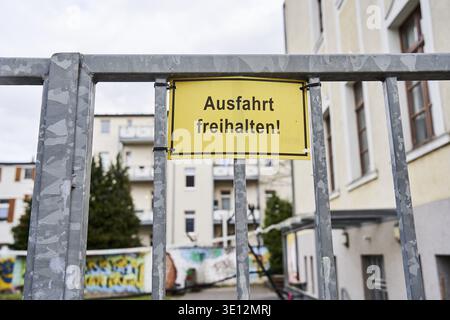 Gelbes Schild mit der Inschrift Ausfahrt halten hängt auf einem grauen Metallgitter vor Wohngebäuden in Magdeburg, Sachsen-Anhalt Stockfoto