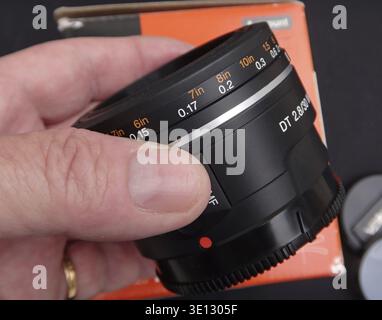 Nahaufnahme eines Fotografen, der ein Sony DT 2.8/30 Makroobjektiv hält und sein kompaktes Design und seine Funktionen zeigt Stockfoto