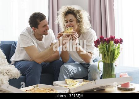 Junges und glückliches Paar, das zu Hause leckere Pizza isst Stockfoto