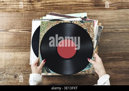 Vinyl-Schallplatten spielen. Musik von einem Vinyl-Plattenspieler hören. Retro- und Vintage-Musikstil. Frau mit analogem LP-Plattenalbum. Stapel alt Stockfoto