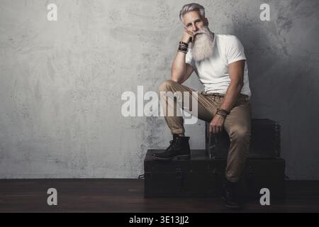 Stilvoller und hübscher bärtiger älterer Mann, der im Studio posiert Stockfoto