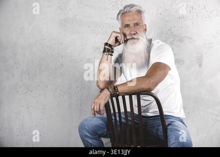 Stilvoller und hübscher bärtiger älterer Mann, der im Studio posiert Stockfoto