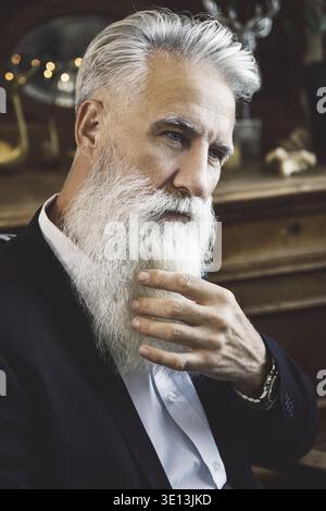 Stilvoller und hübscher bärtiger älterer Mann, der im Studio posiert Stockfoto